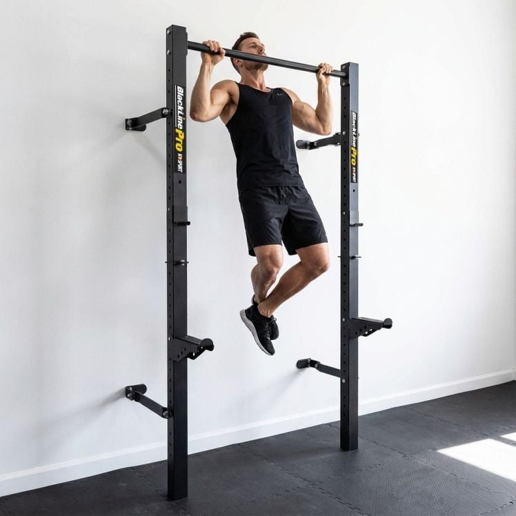 Mann macht Klimmzug an wandmontiertem klappbarem Half Rack