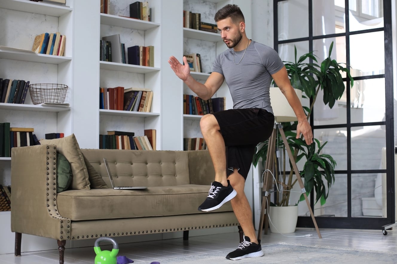 Mann macht intensives HIIT-Training zu Hause im Wohnzimmer – kurzes 20-Minuten-Workout für die Feiertage