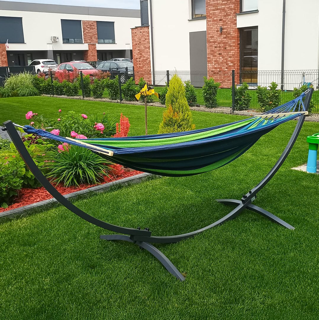 Hamaca para exteriores con estructura estable sobre un cuidado césped delante de una moderna vivienda con parterre de flores