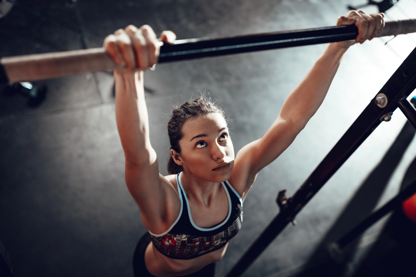 Mujer entrena dominadas en una barra en el gimnasio y se prepara para su primera dominada