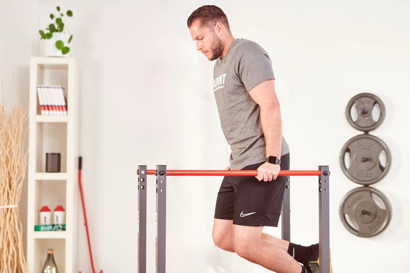Atleet voert dips uit op parallelle bars – oefening voor borst en triceps