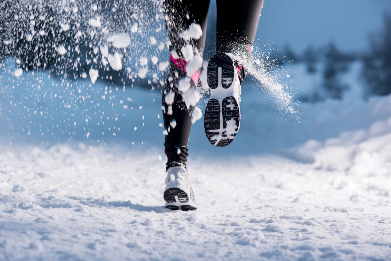 Allenamento all'aperto in inverno: Corridore fa jogging in un paesaggio innevato e solleva la neve